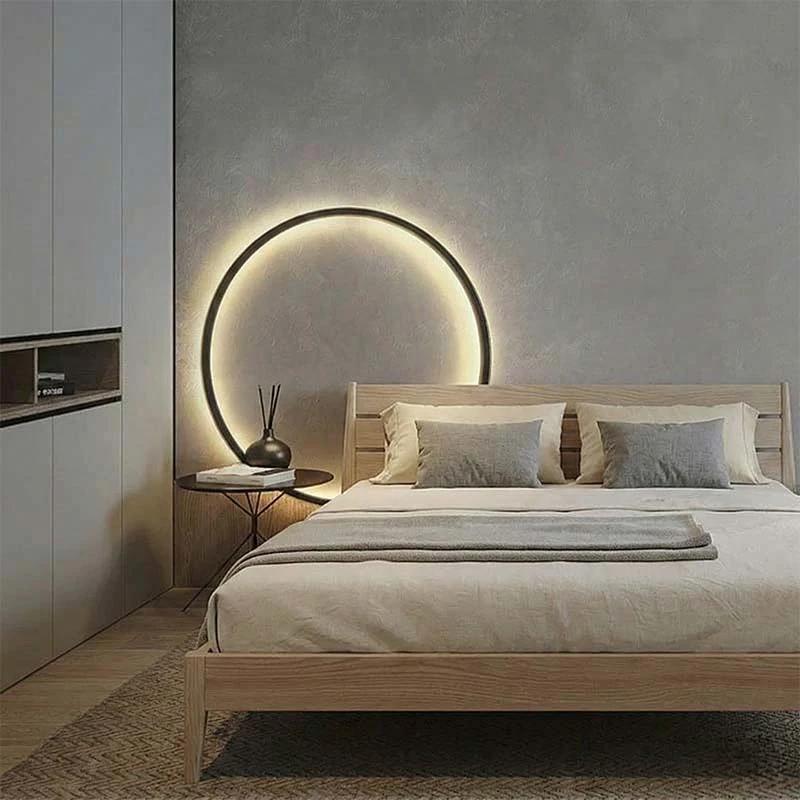 KRETS – Ring LED Wall Lamp, black ring with warm glow mounted above bed in a modern Nordic bedroom.