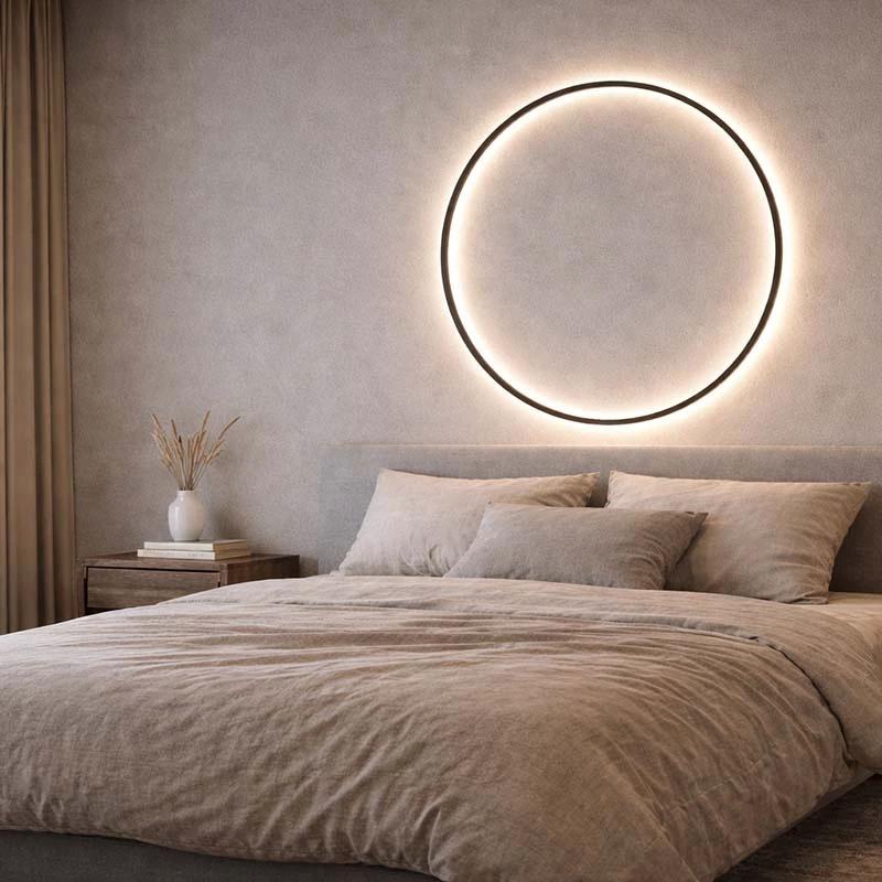 KRETS – Ring LED Wall Lamp; black circular wall light above a bed in a beige bedroom.