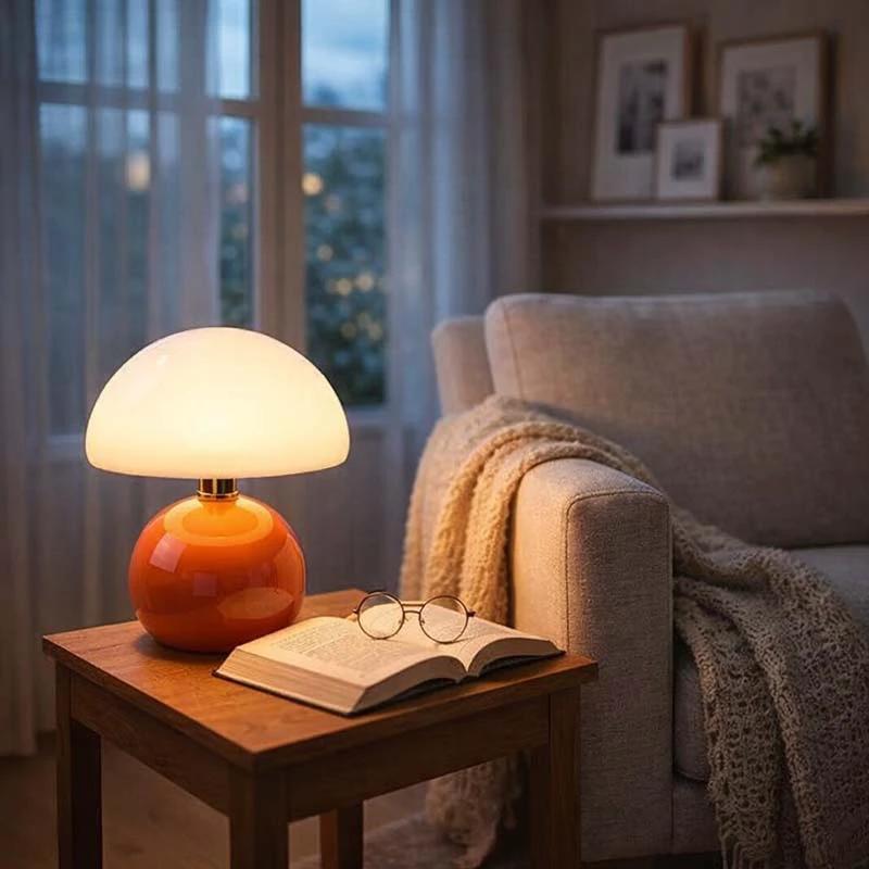 Nordic Ceramic Mushroom Table Lamp with orange ceramic base and white dome shade on a wooden side table beside a sofa.