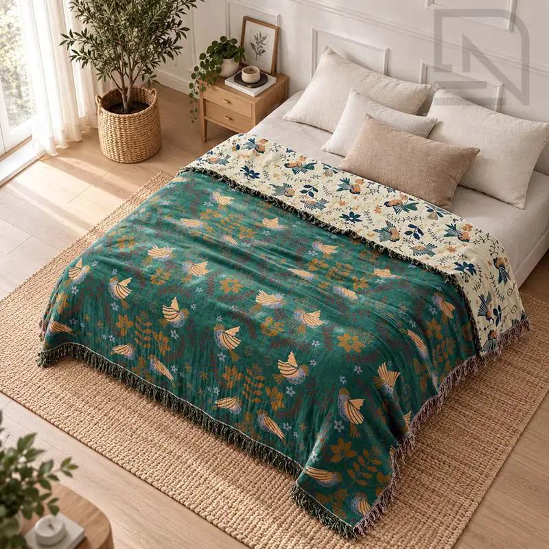 100% Cotton Reversible Throw Blanket on a bed in a bedroom; teal with bird motifs, Nordic Essentials