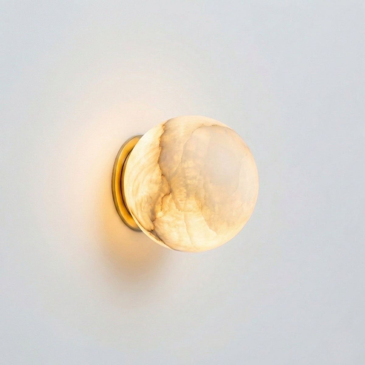 Wall-mounted light fixture with a gold frame and beige glass shade on a light gray background