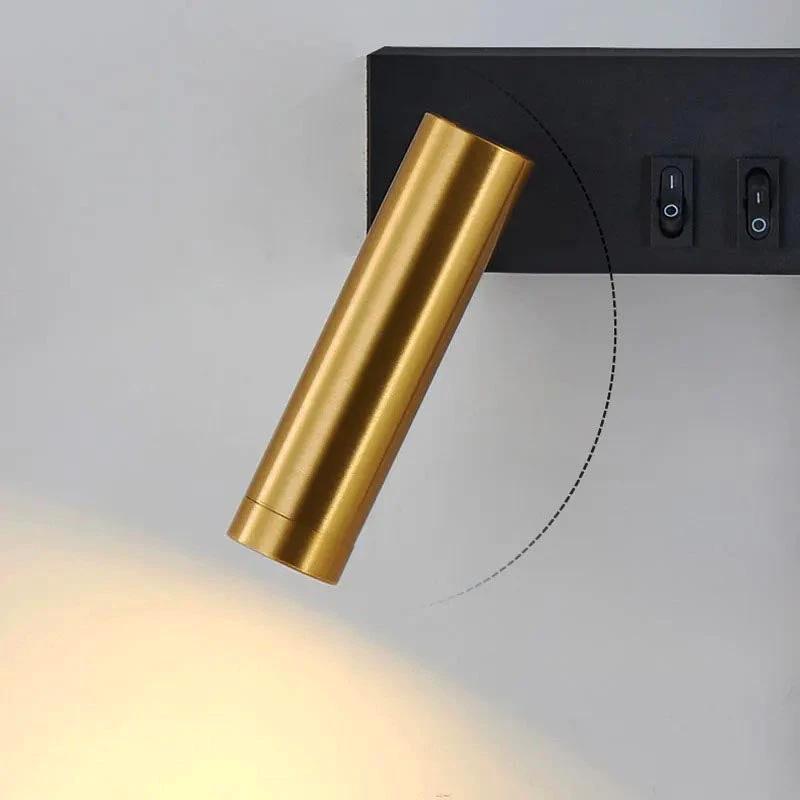 SVEA – Swivel LED Wall Light, brass cylindrical reading lamp mounted on a bedroom wall beside a switch panel.
