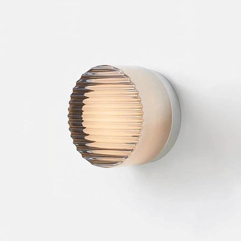 LED Wall Sconce on white wall; amber ribbed glass globe, minimalist metal backplate.
