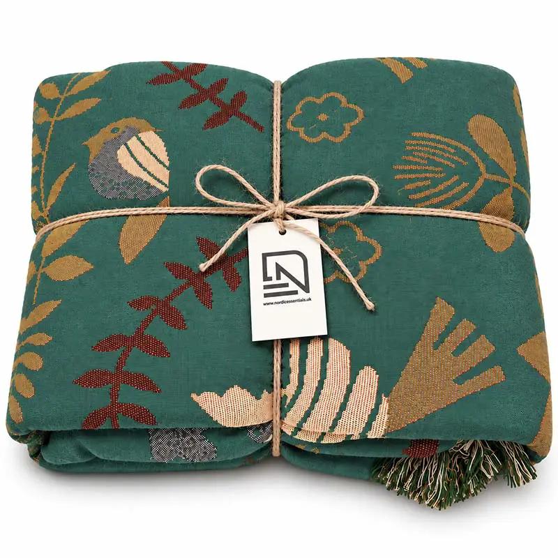100% Cotton Reversible Throw Blanket with teal bird-pattern print, folded for sofa or bed, Nordic Essentials.