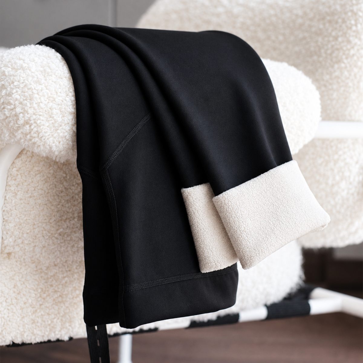Black maternity thick fleece leggings with belly support panel draped over a chair