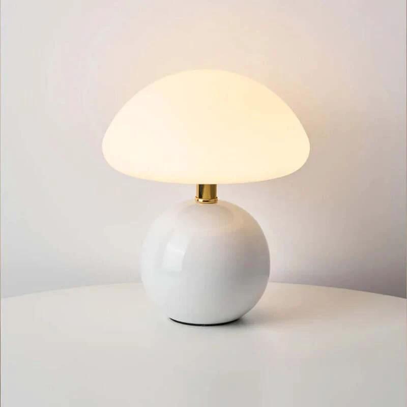 White modern ceramic table lamp with a gold base on a light grey surface and background